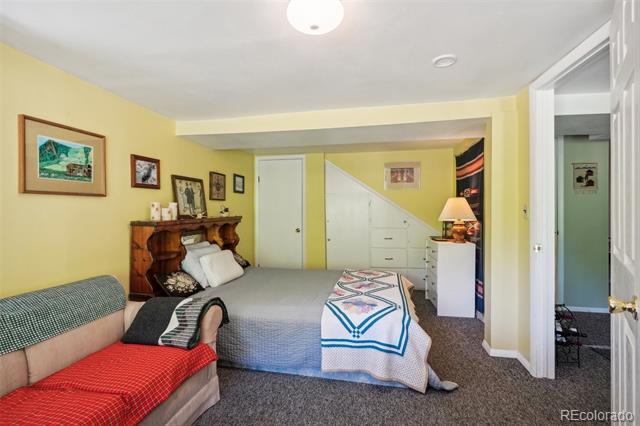 Bedroom with yellow walls, a gray bed, and a red-and-green upholstered bench.