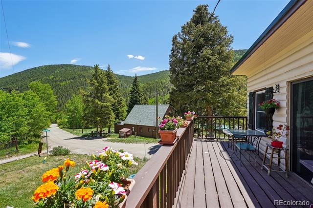 Wooden deck overlooking a flower garden and forested mountain views.