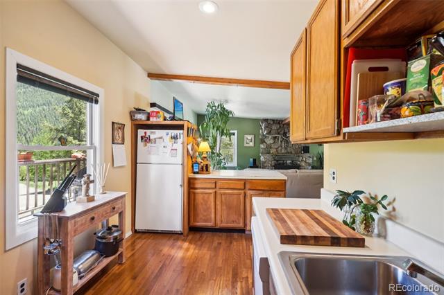 Kitchen with wood cabinetry, butcher-block counters, hardwood floors, and a wooded view through the window.