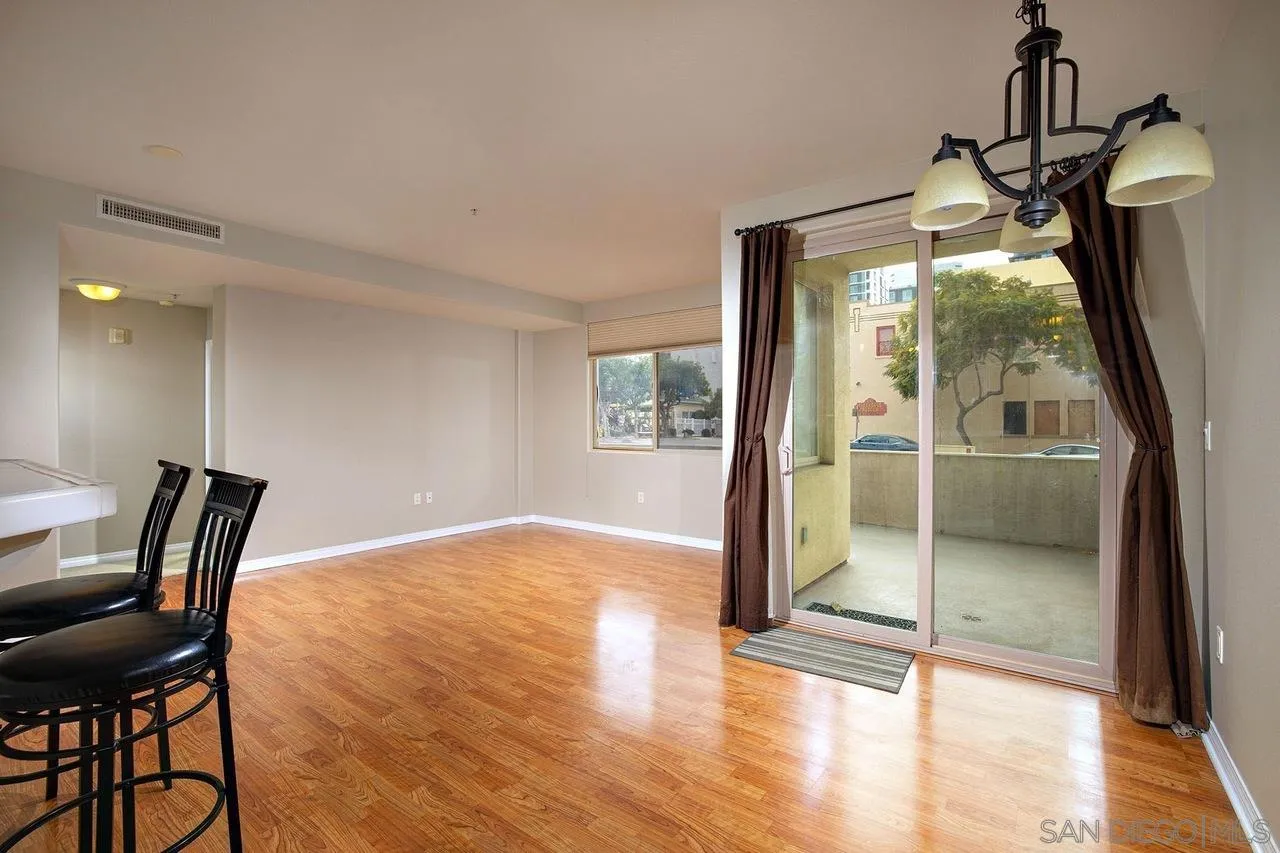Dining area with hardwood floors, black chairs, and a sliding glass door to a balcony.