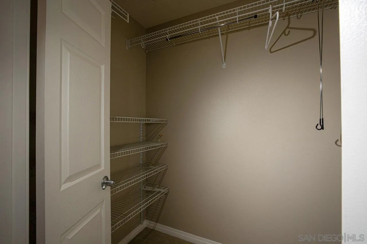 Empty walk-in closet with white wire shelving and a hanging rod.