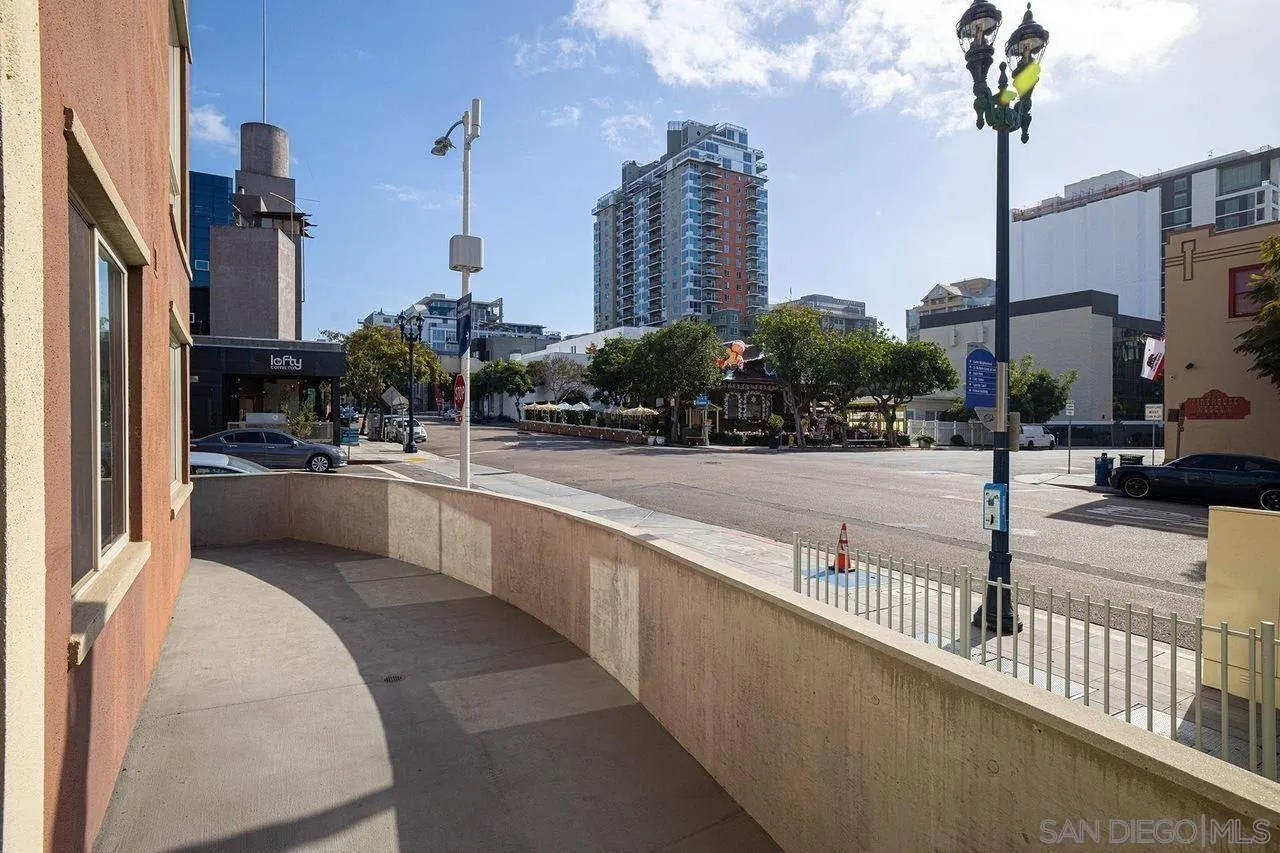 Exterior patio overlooking a downtown street, with a curved wall and high-rise buildings beyond.