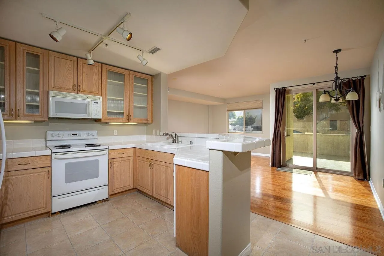 Kitchen with light wood cabinets, white appliances, and sliding glass doors to a patio.