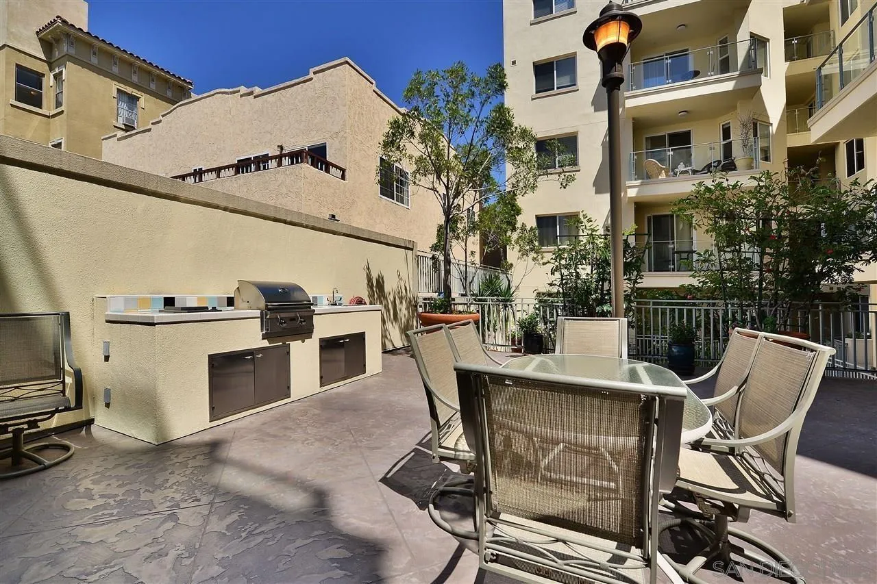 Shared courtyard patio with a built-in grill, outdoor dining set, and apartment balconies.