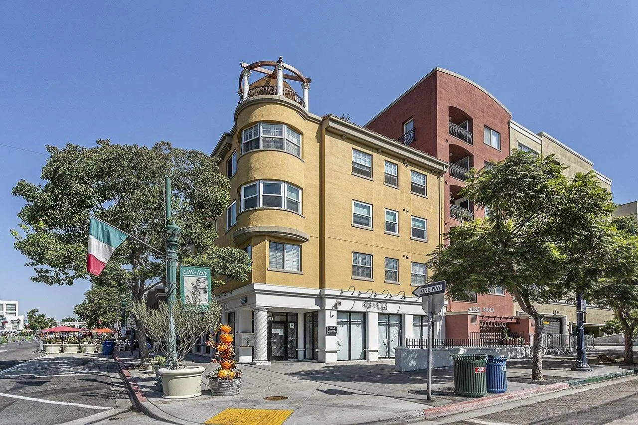 Street-corner building at 1601 India St, with a rounded yellow facade and Italian flag.