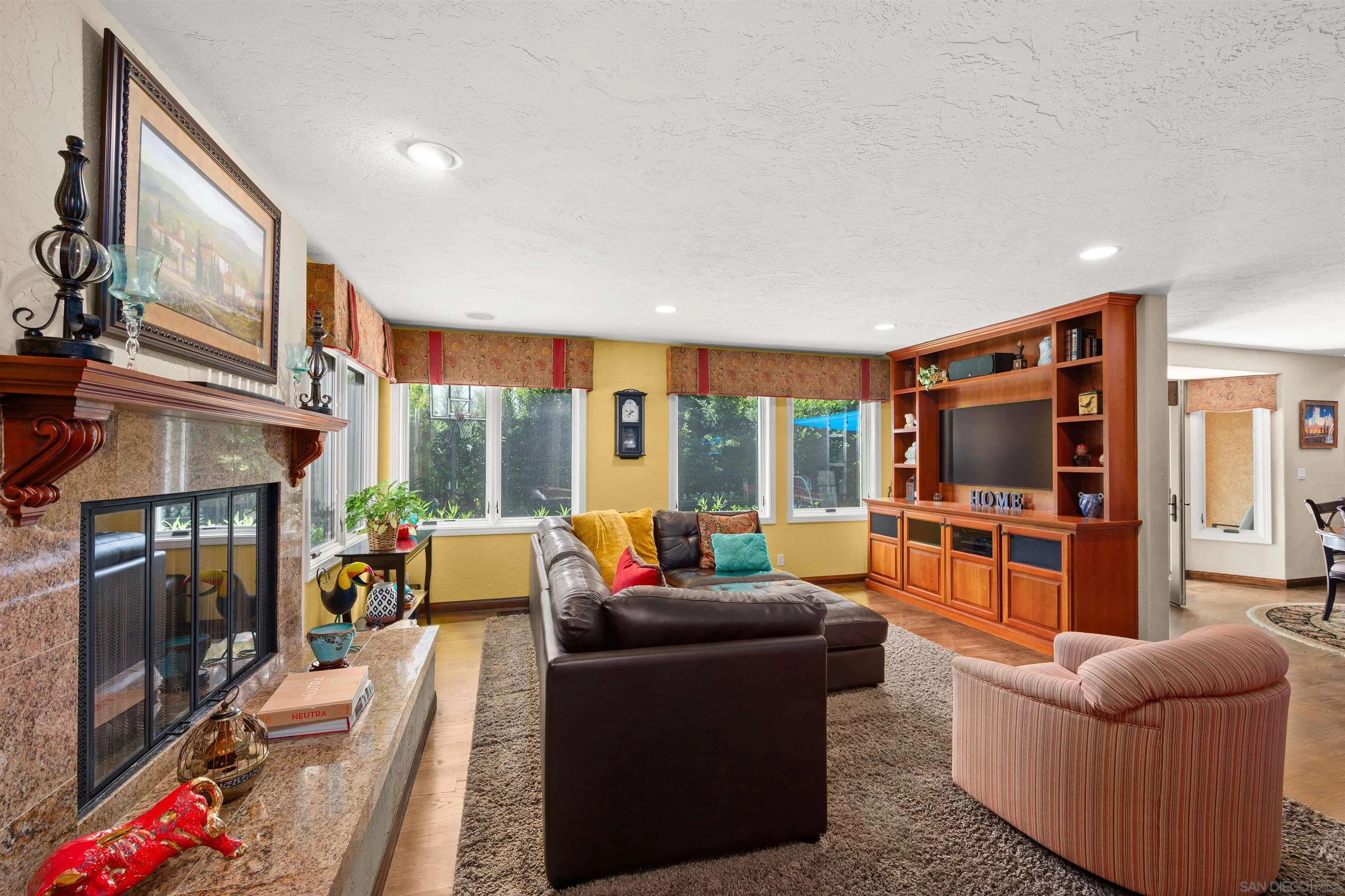 Living room with a stone fireplace, leather sectional, and built-in entertainment center.