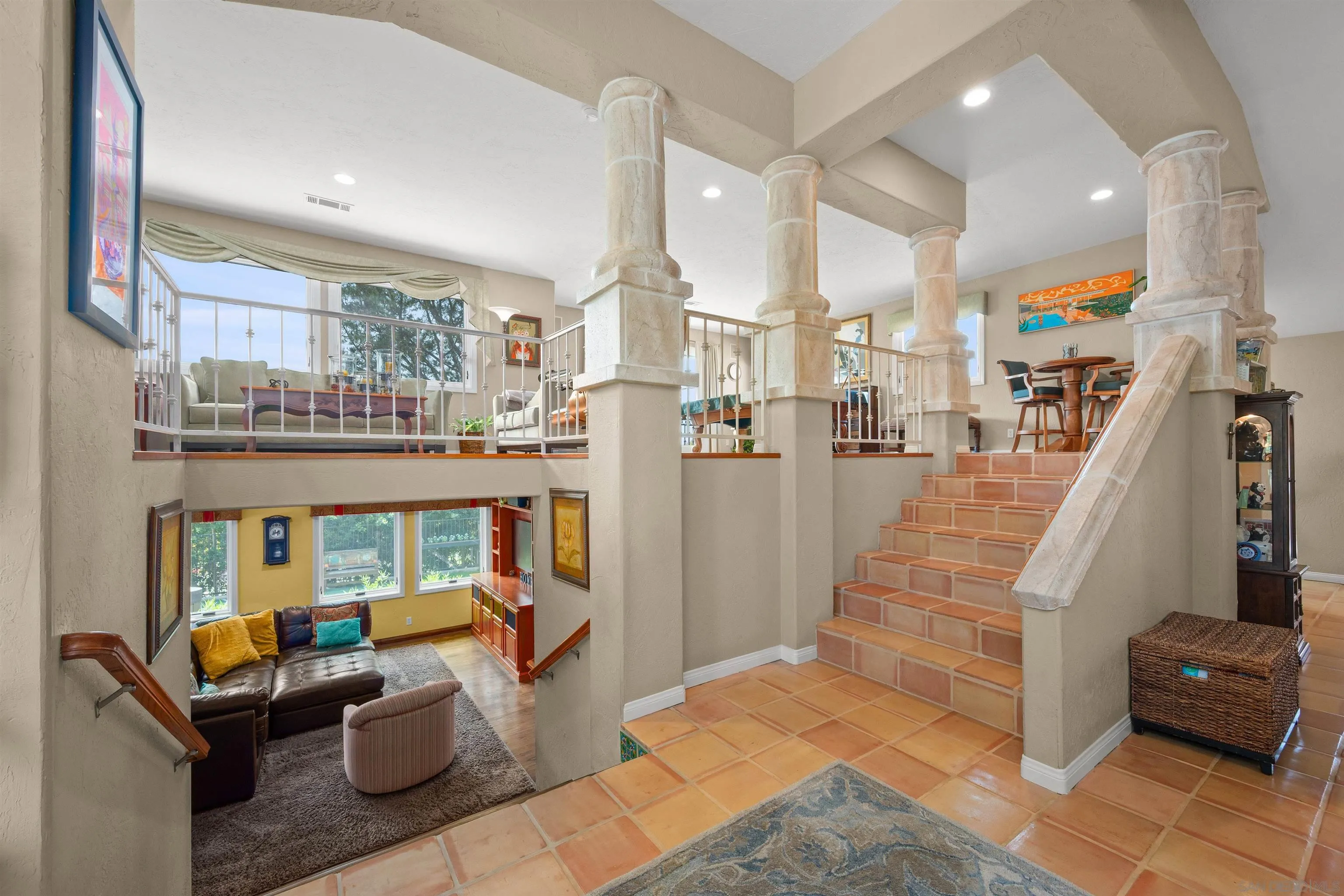Split-level foyer with terracotta stairs, stone-look columns, and living areas on both levels.