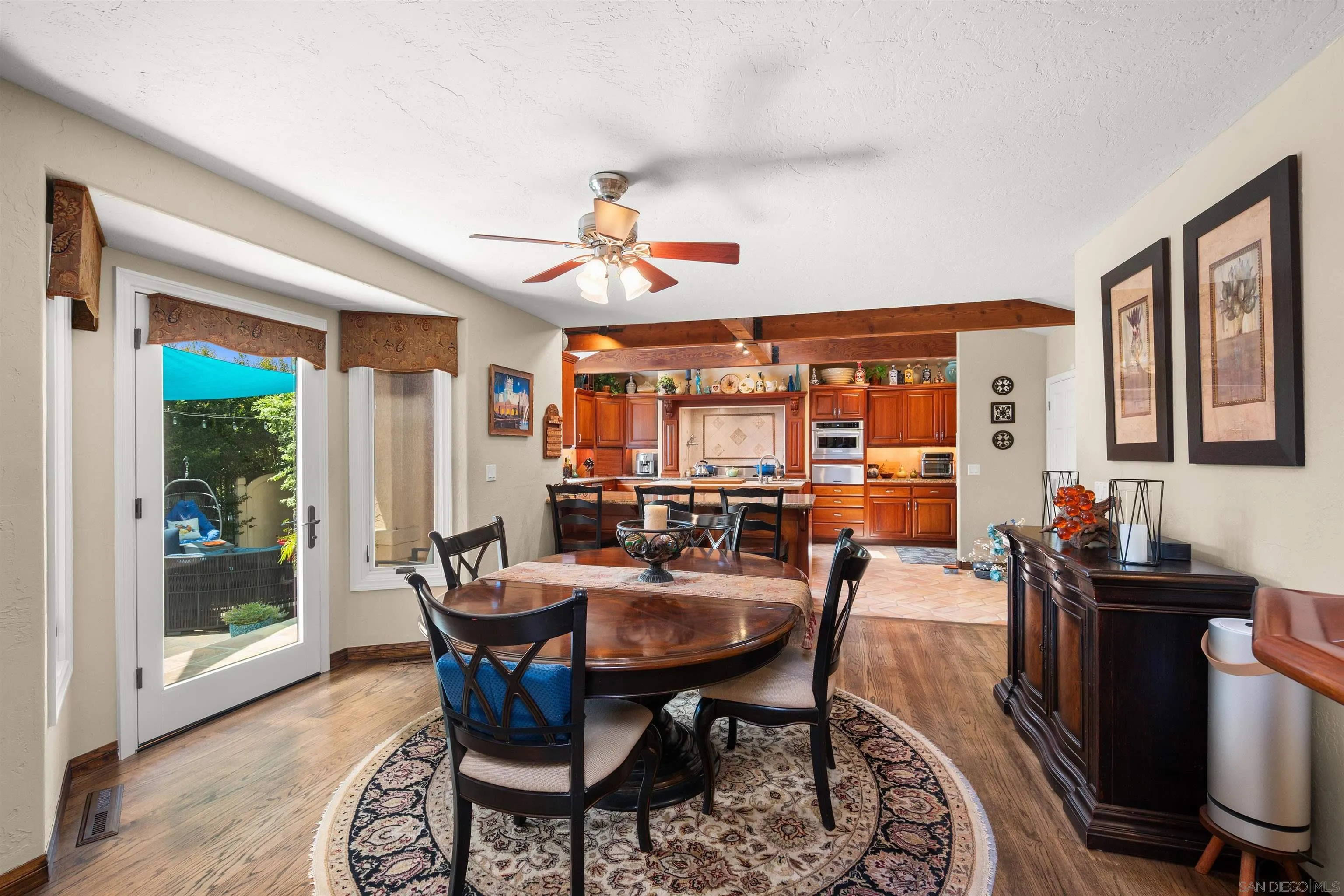 Dining room with an oval table and patterned rug, opening into a wood-cabinet kitchen.