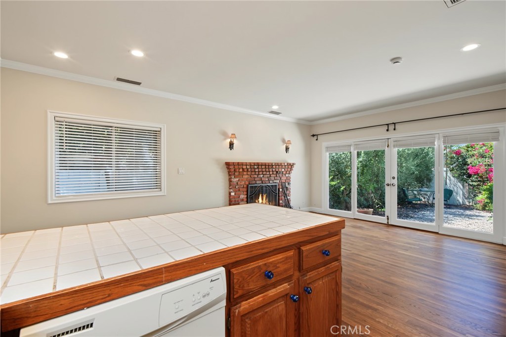 Kitchen with tiled island, brick fireplace, and glass doors opening to a garden.