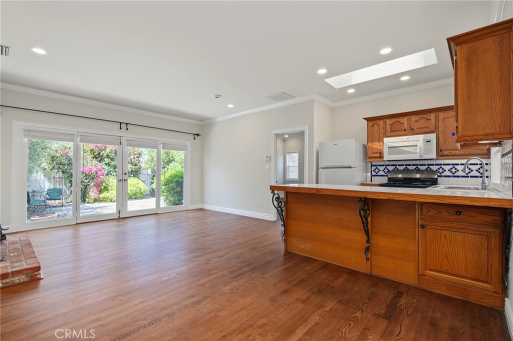 Vacant kitchen and dining area with wood cabinetry, hardwood floors, and garden-facing sliding glass doors.