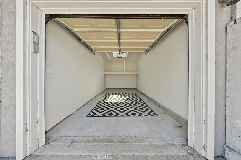 Empty garage with a raised door and black-and-white geometric rug.