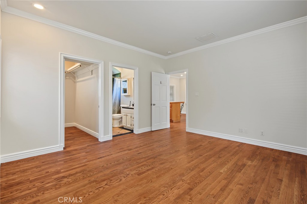 Vacant bedroom with hardwood floors, a closet, and an adjoining bathroom.