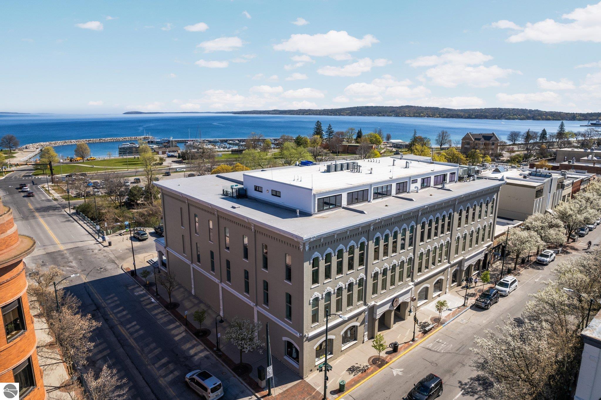 Aerial view of a downtown commercial building beside a marina and blue lake.