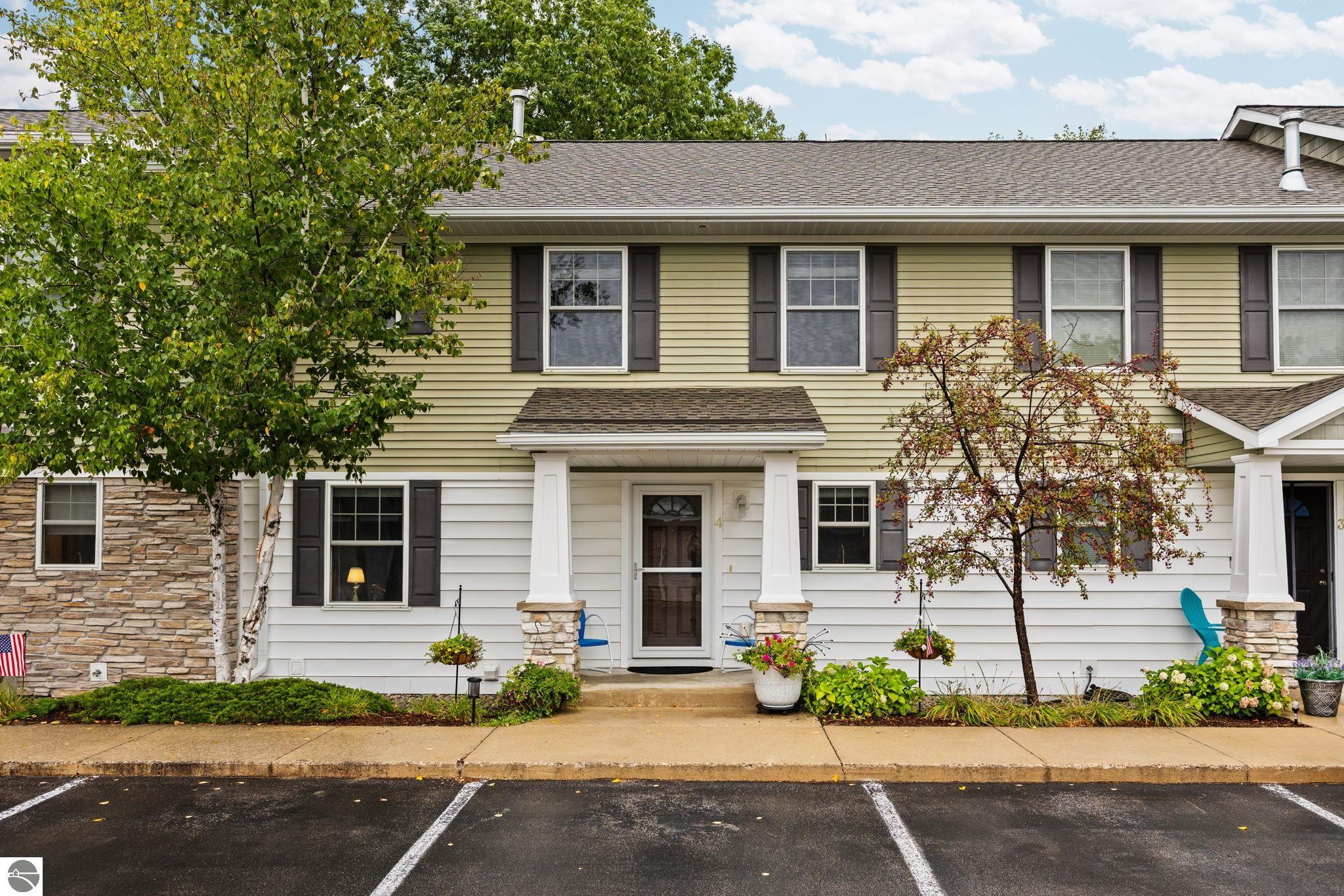 Two-story townhouse with a covered entry, stone accents, and landscaped front garden.