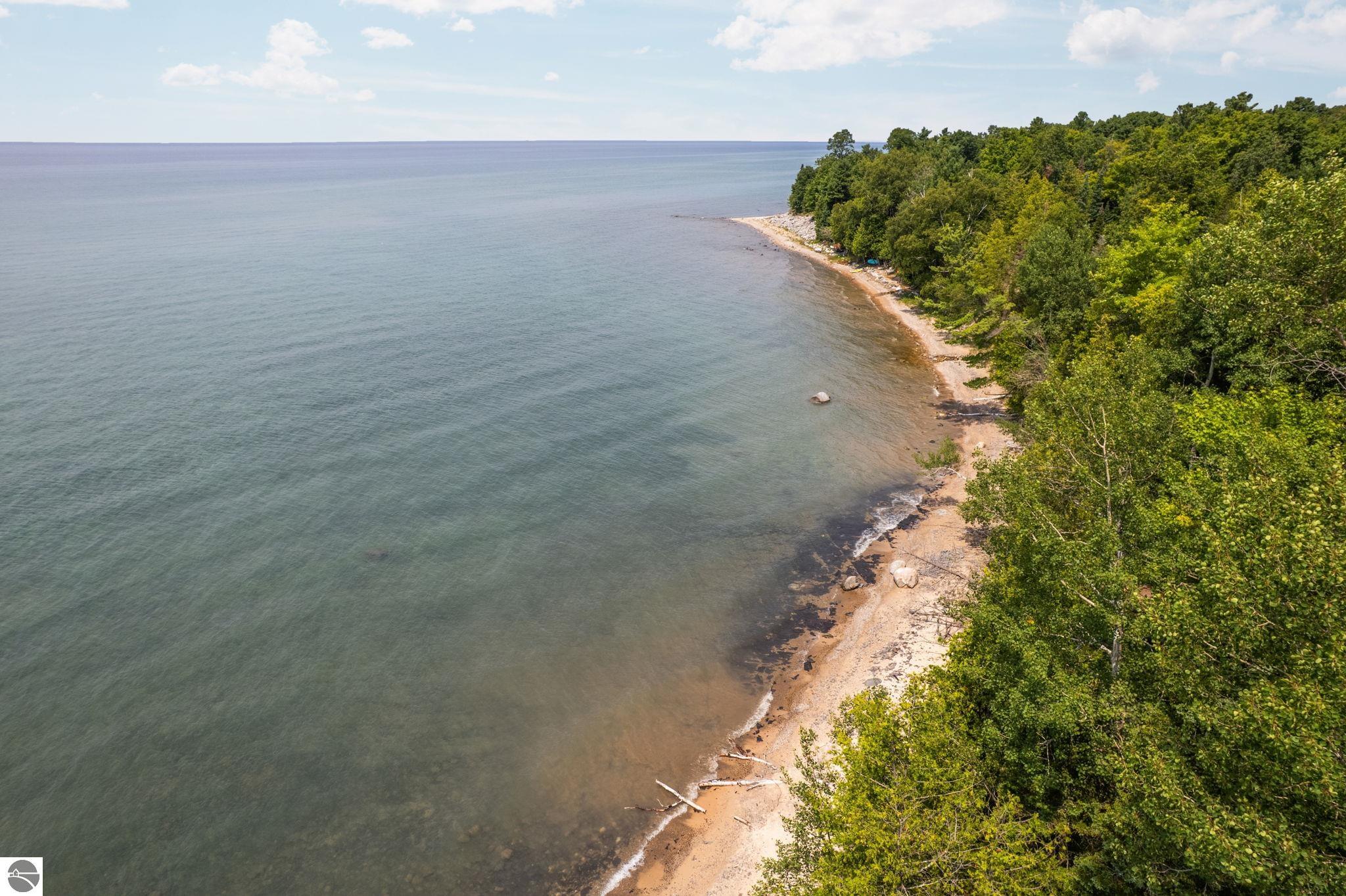 Aerial view of a wooded shoreline curving along a broad lake.