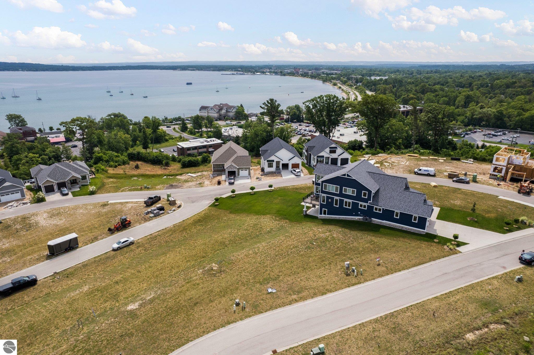 Aerial view of homes under construction beside a bay with sailboats.
