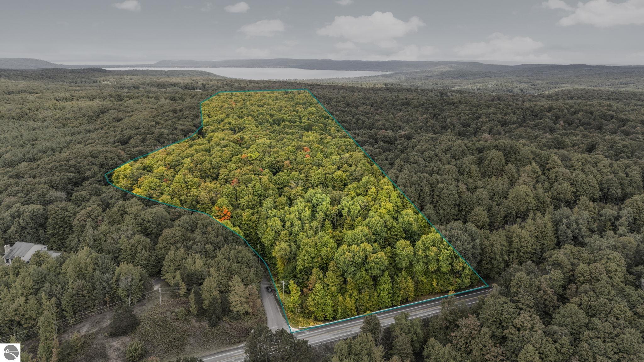 Outlined wooded parcel with road frontage and a lake visible in the distance.