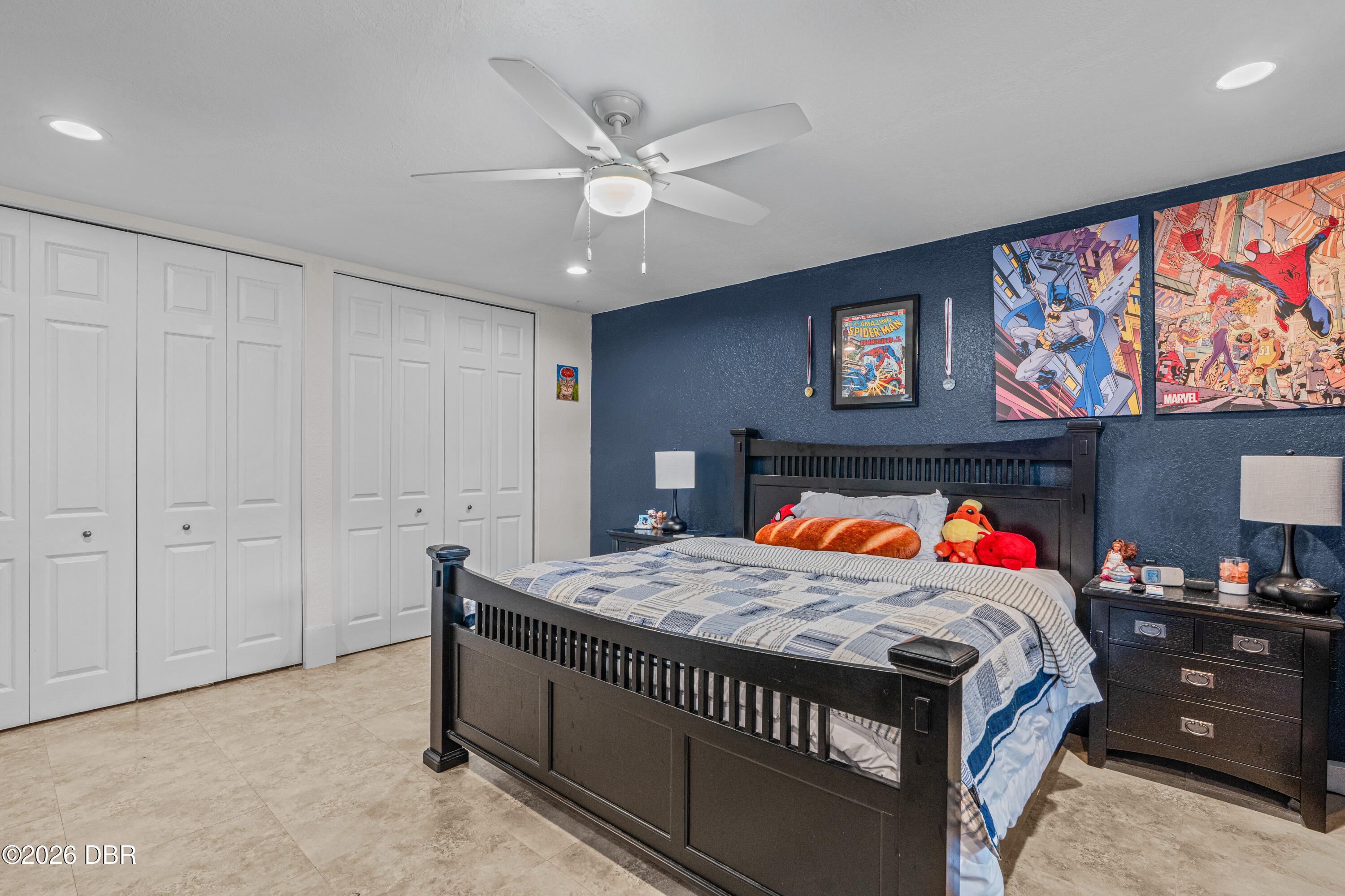 Bedroom with a dark wood bed, navy superhero-art wall, and white double closet doors.
