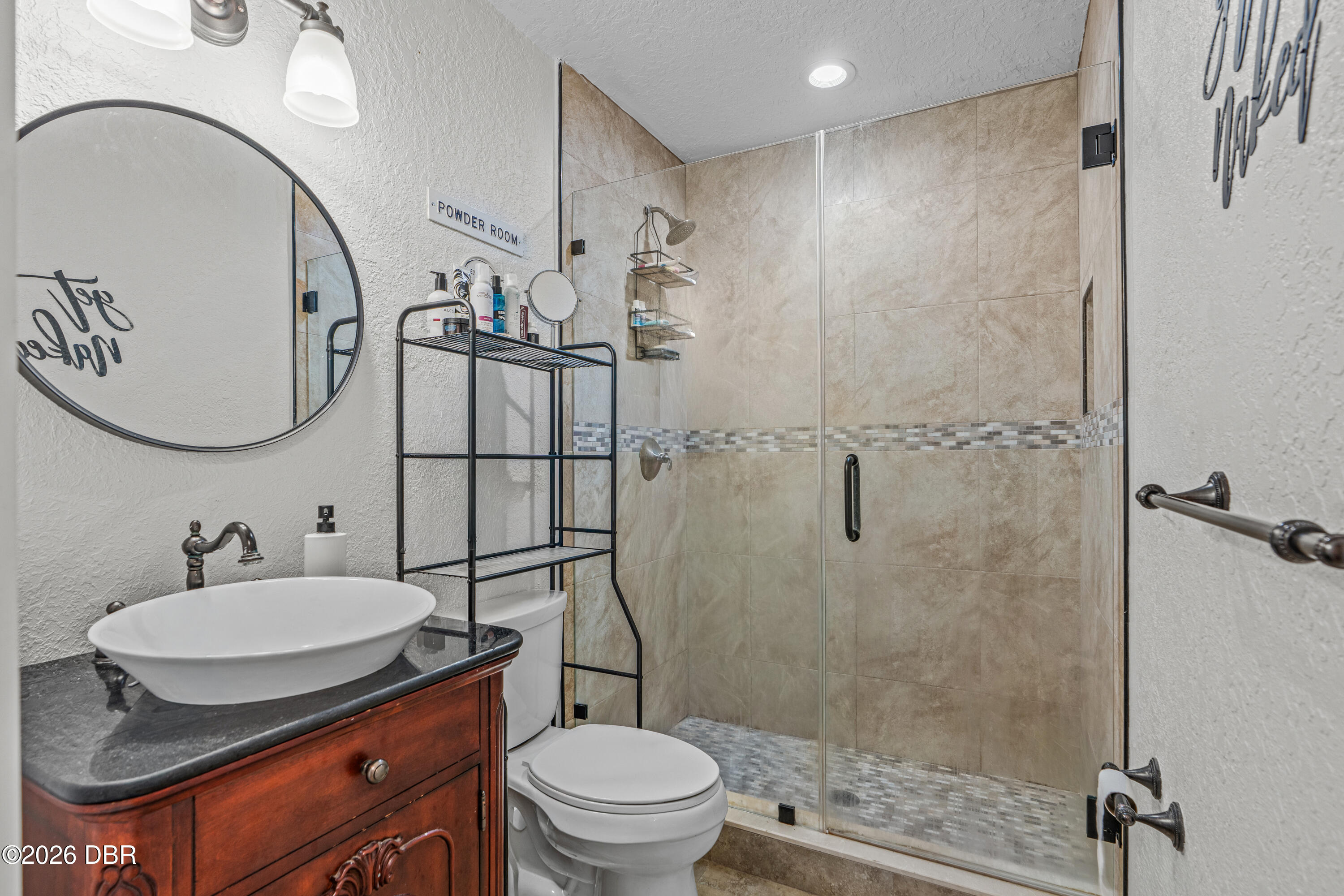 Bathroom with a carved wood vanity, vessel sink, and glass-enclosed tiled shower.