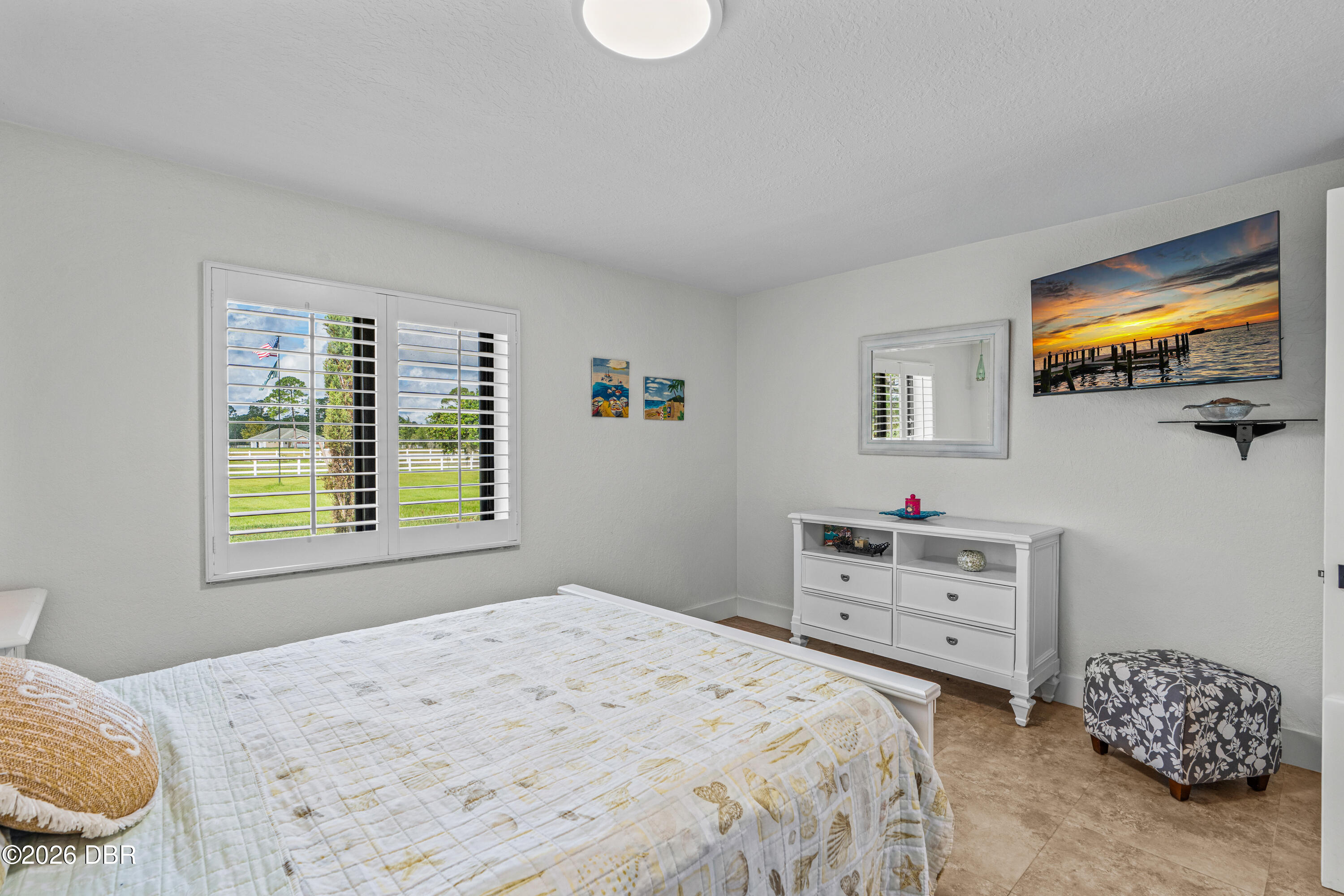 Bedroom with a white bed, plantation shutters, and a dresser.