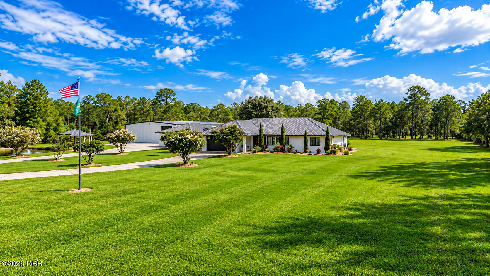 Single-story home with a metal roof, broad manicured lawn, and American flag.