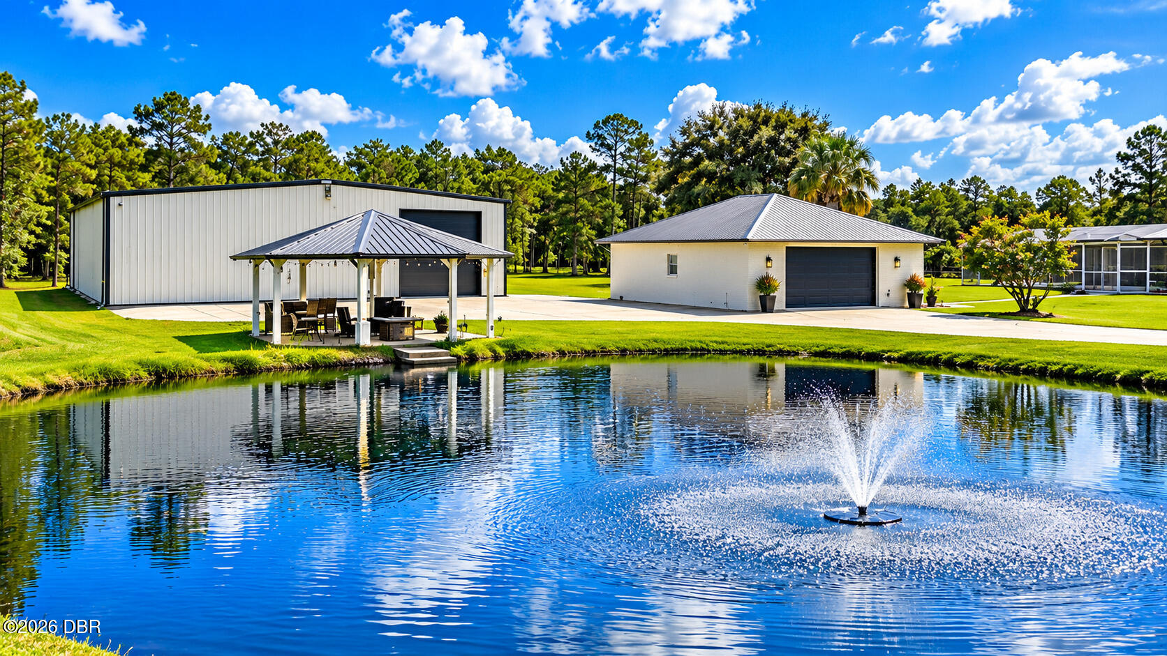 Property outbuildings and covered pavilion beside a pond with a fountain.