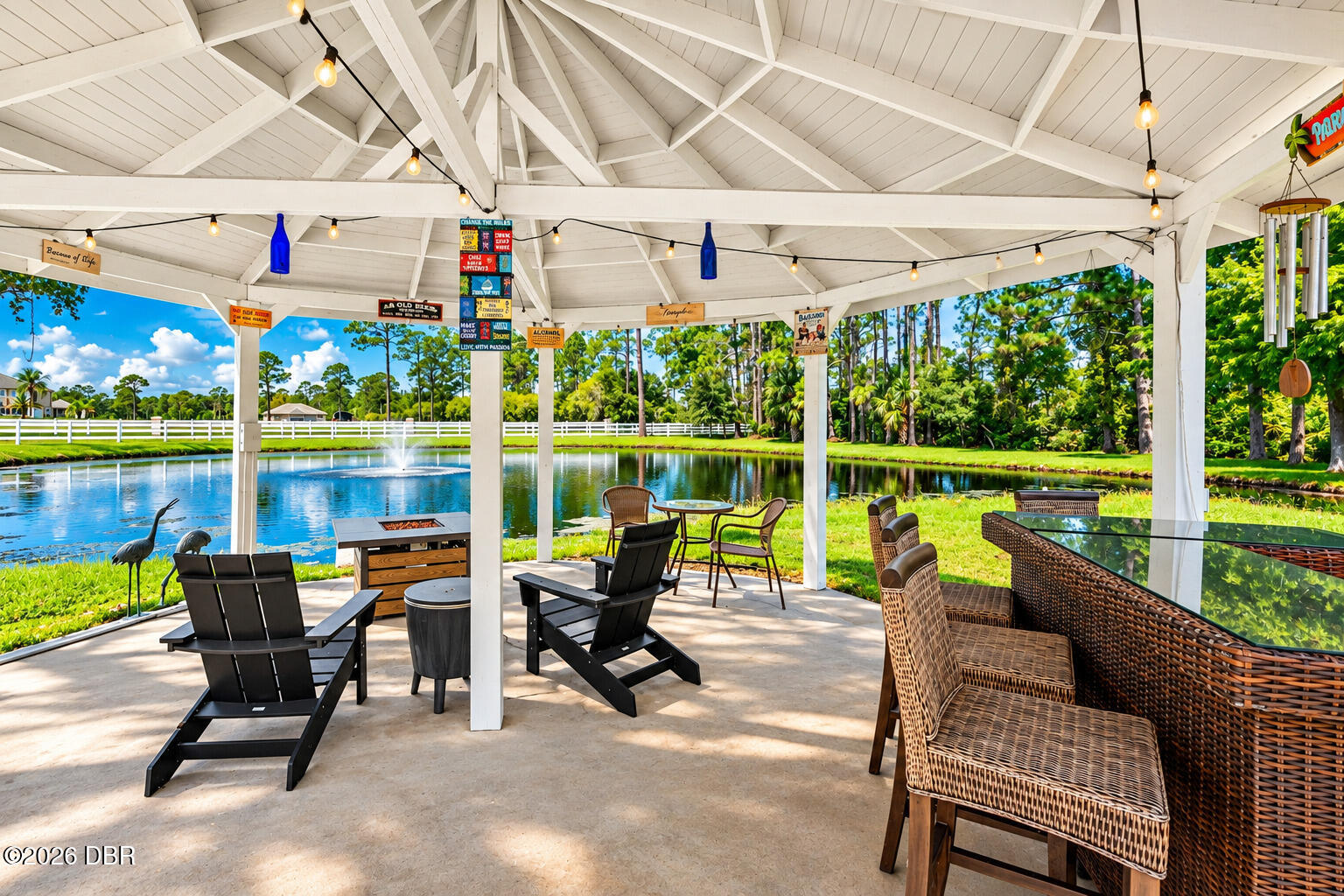 Covered pavilion patio with outdoor seating overlooking a pond and fountain.