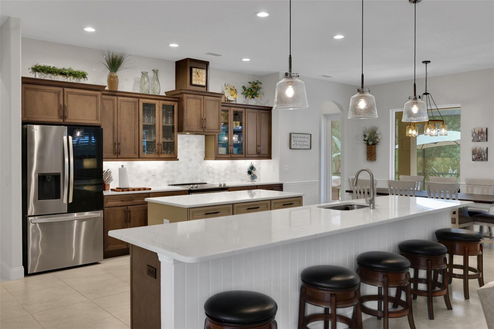 Kitchen with dark wood cabinets and a large white island lined with bar stools.