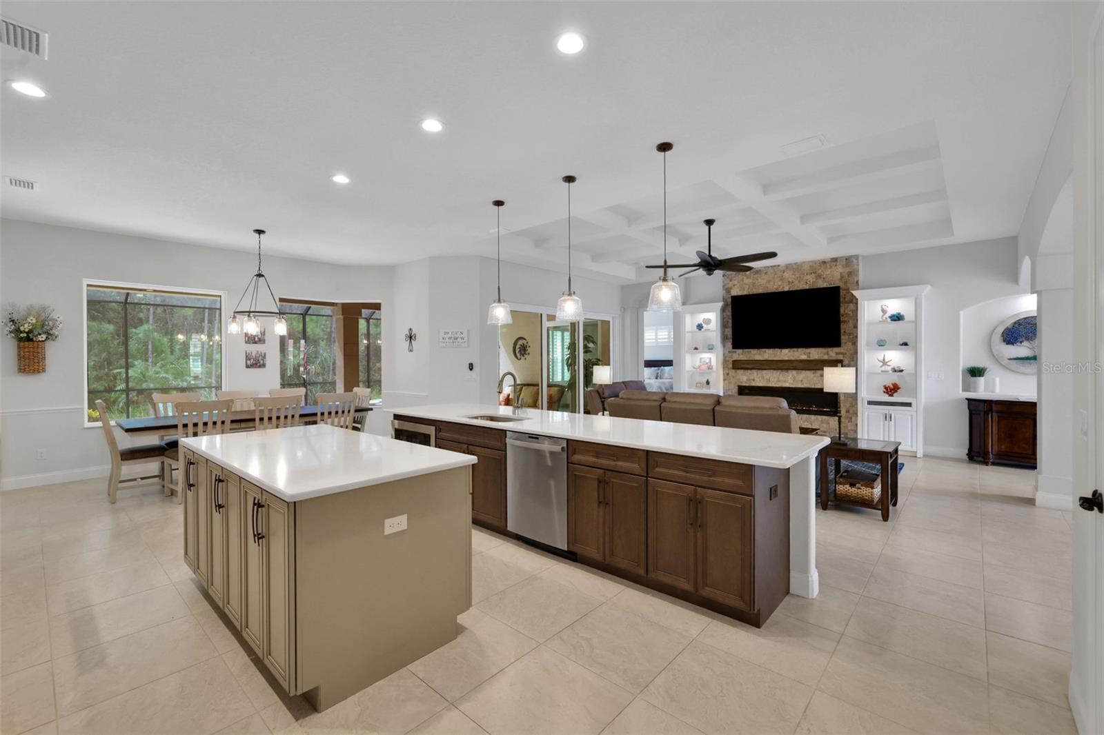 Open-plan kitchen with two large islands, dark wood cabinets, and a stone fireplace.