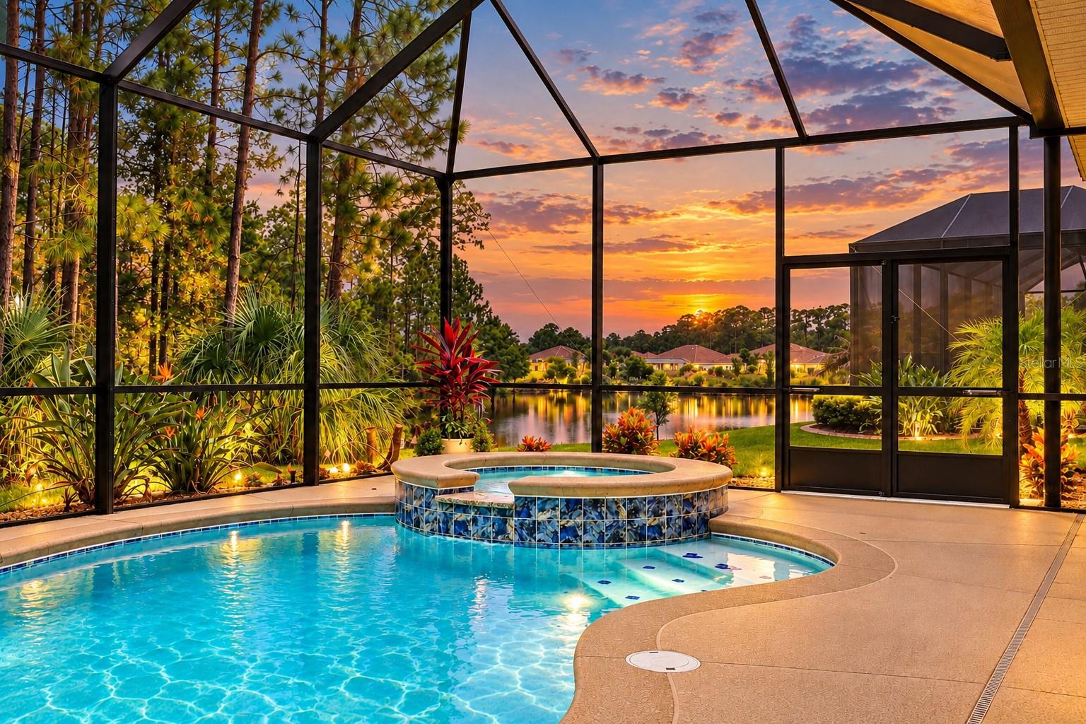Screened pool and raised spa overlook a pond beneath a colorful sunset.