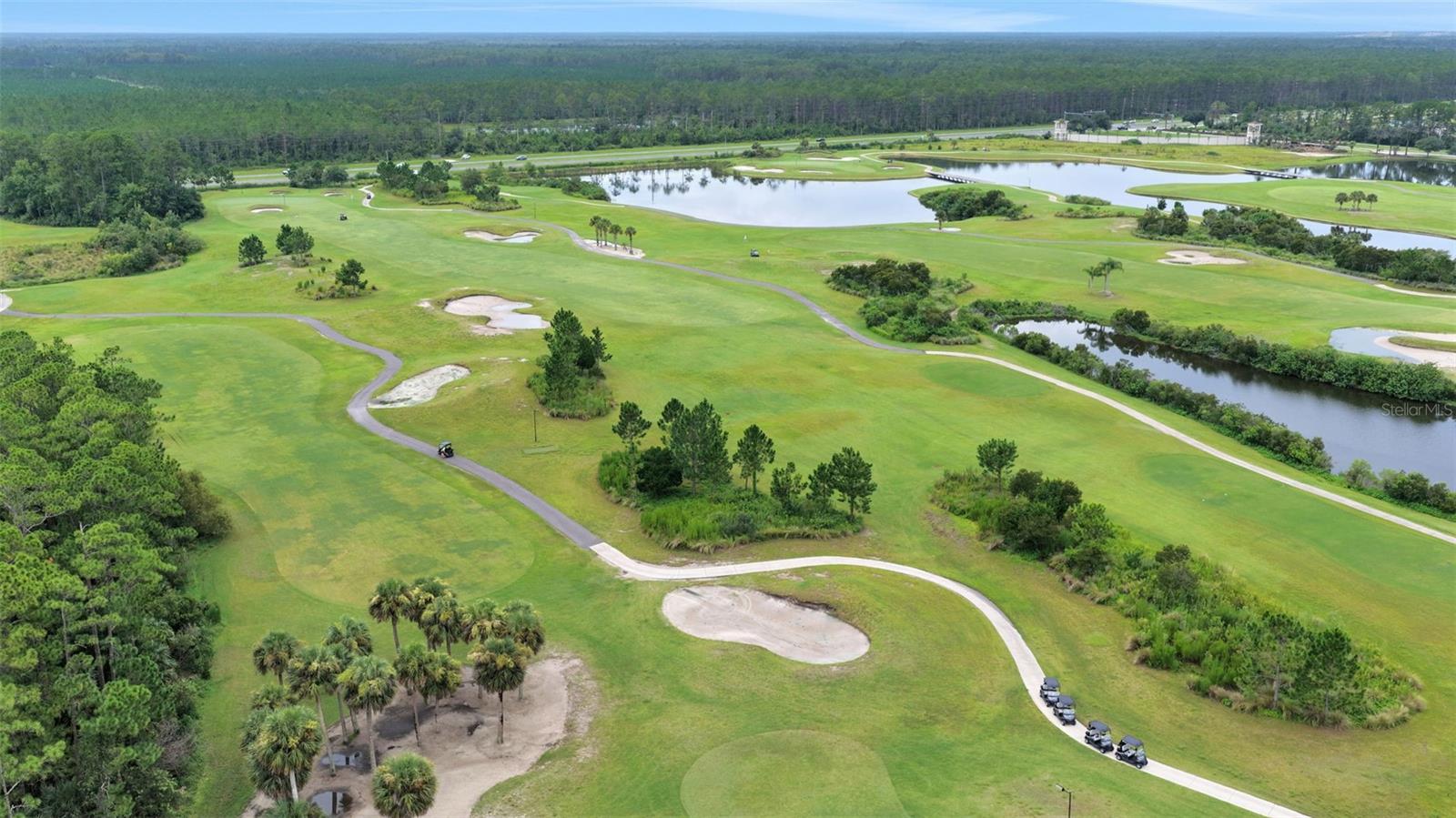 Aerial view of a golf course with ponds, sand bunkers, and winding cart paths.