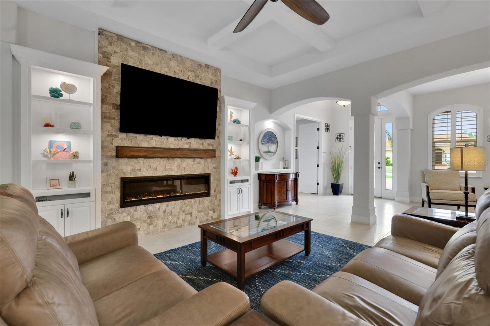 Living room with a stone fireplace wall, built-in shelves, and beige sectional seating.