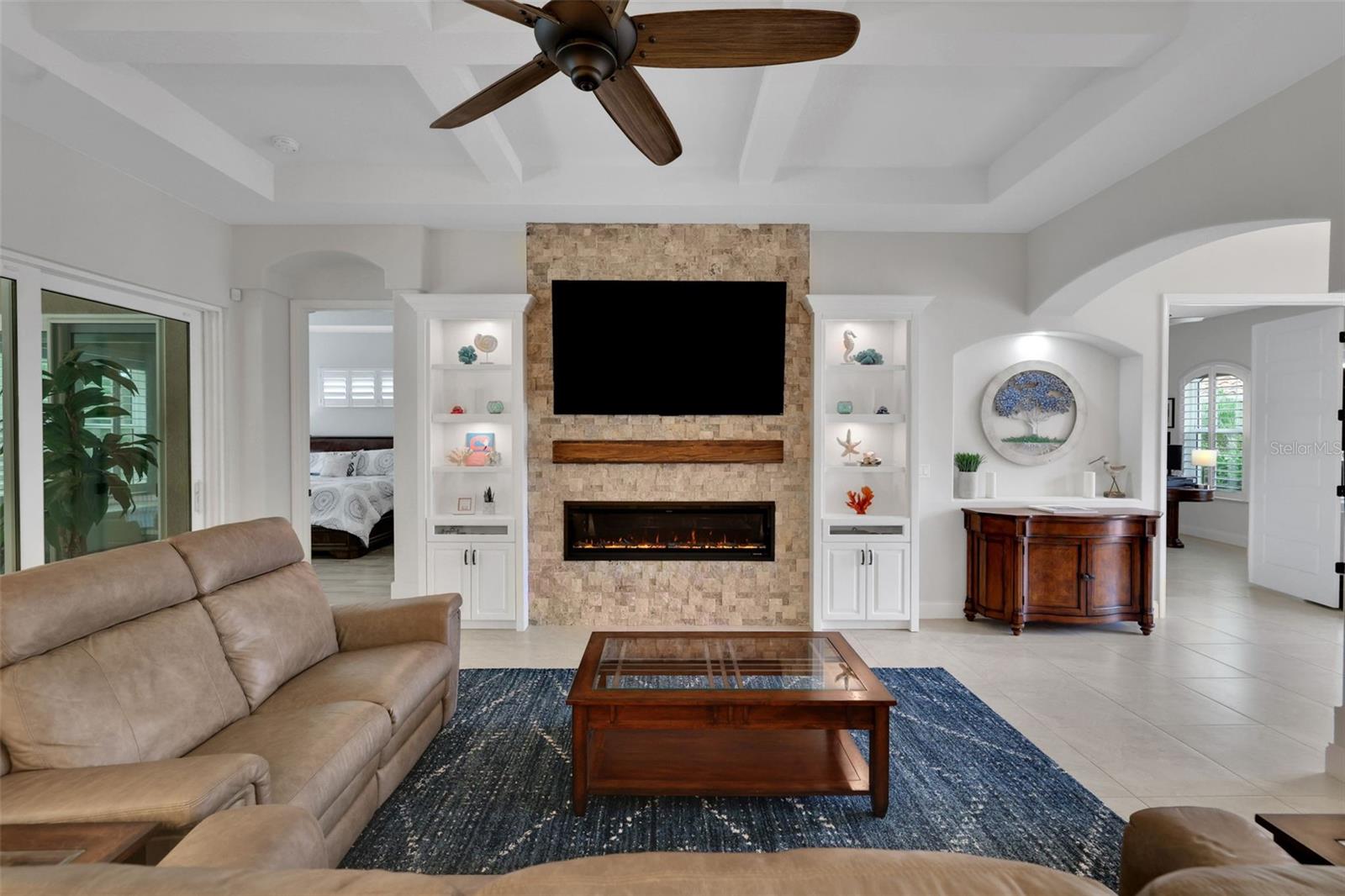 Living room with a stone fireplace wall, built-in shelves, and beige sectional sofas.