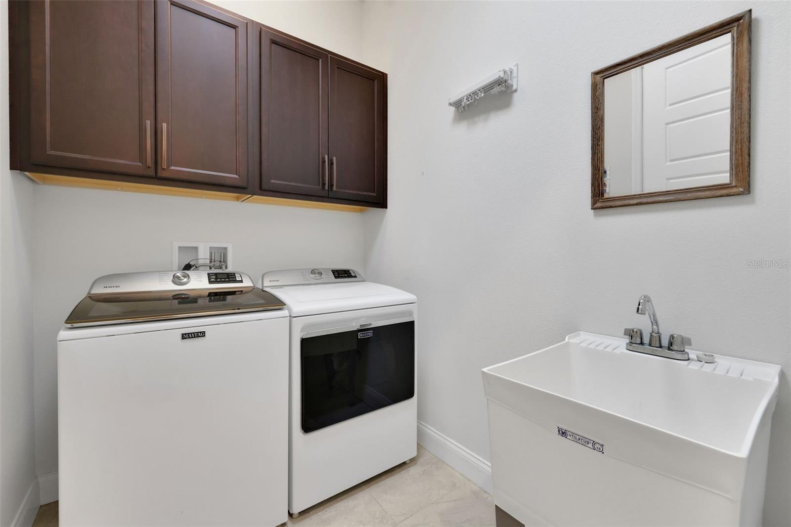 Laundry room with washer, dryer, overhead cabinets, and a deep utility sink.