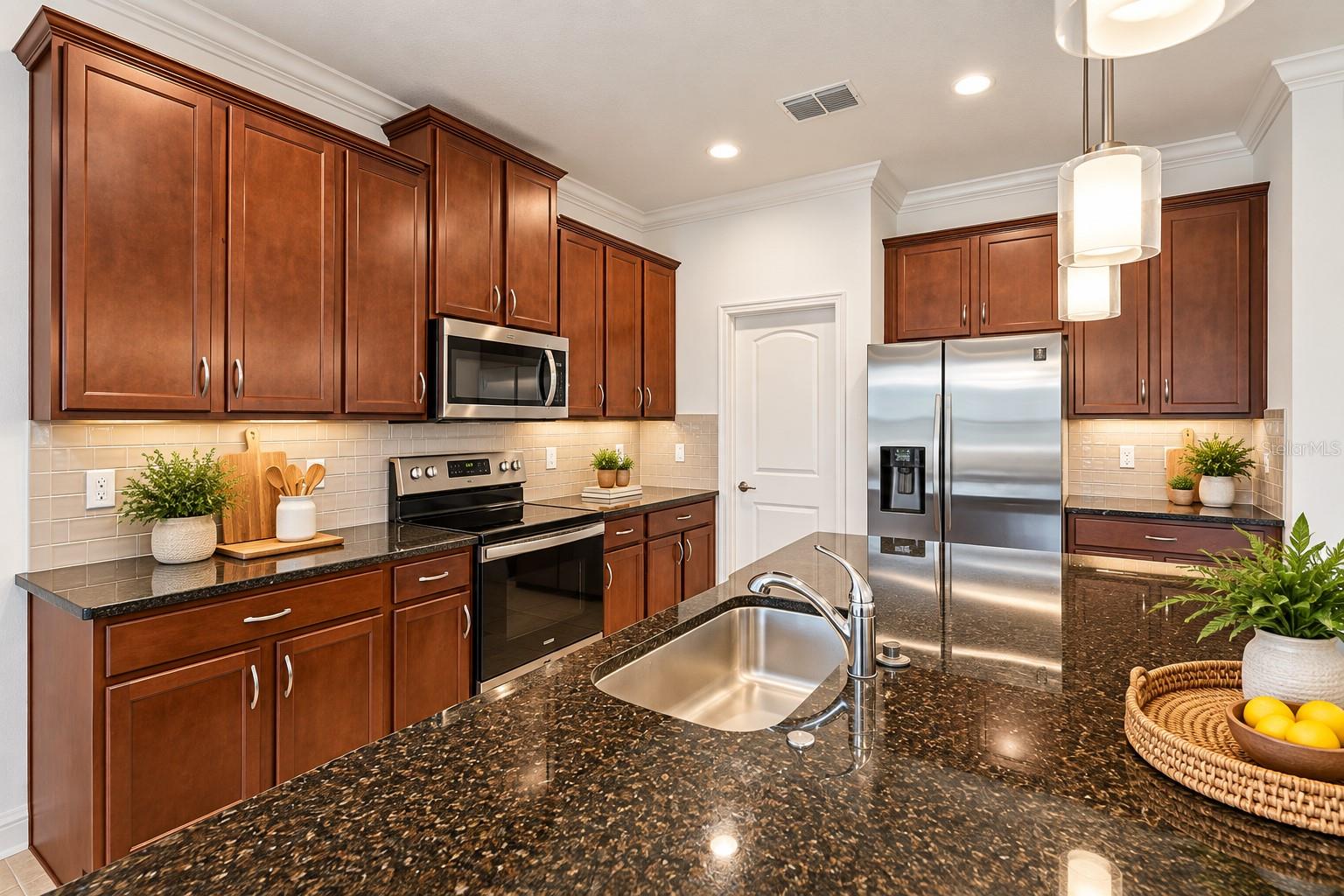 Kitchen with cherry cabinets, granite counters, stainless steel appliances, and a large sink island.