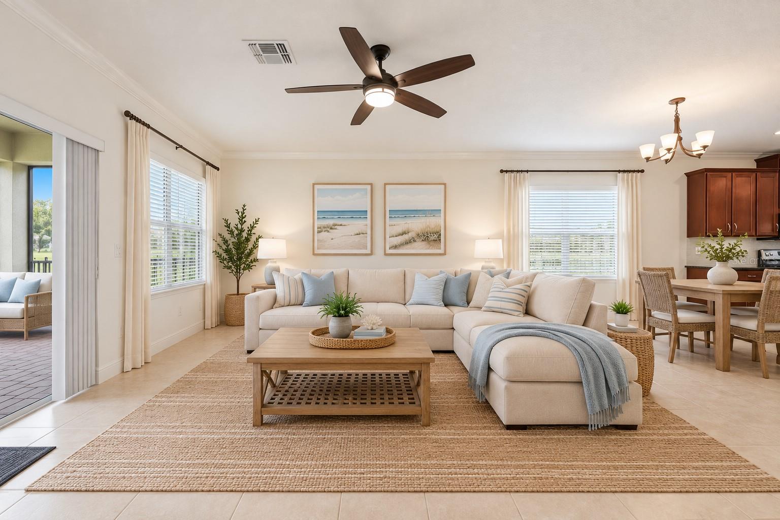 Staged living room with a cream sectional, woven rug, beach prints, and an open dining area.