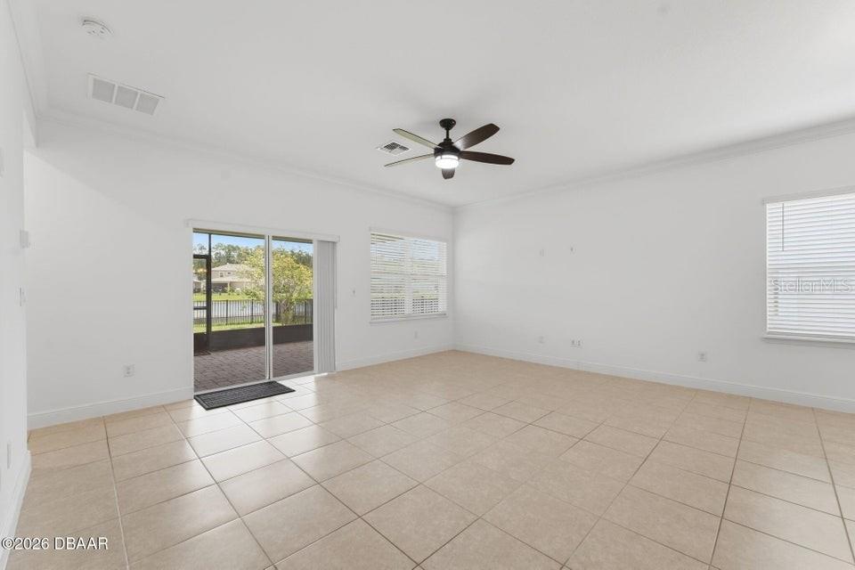 Living room with beige tile flooring, a ceiling fan, and sliding glass doors to a patio.