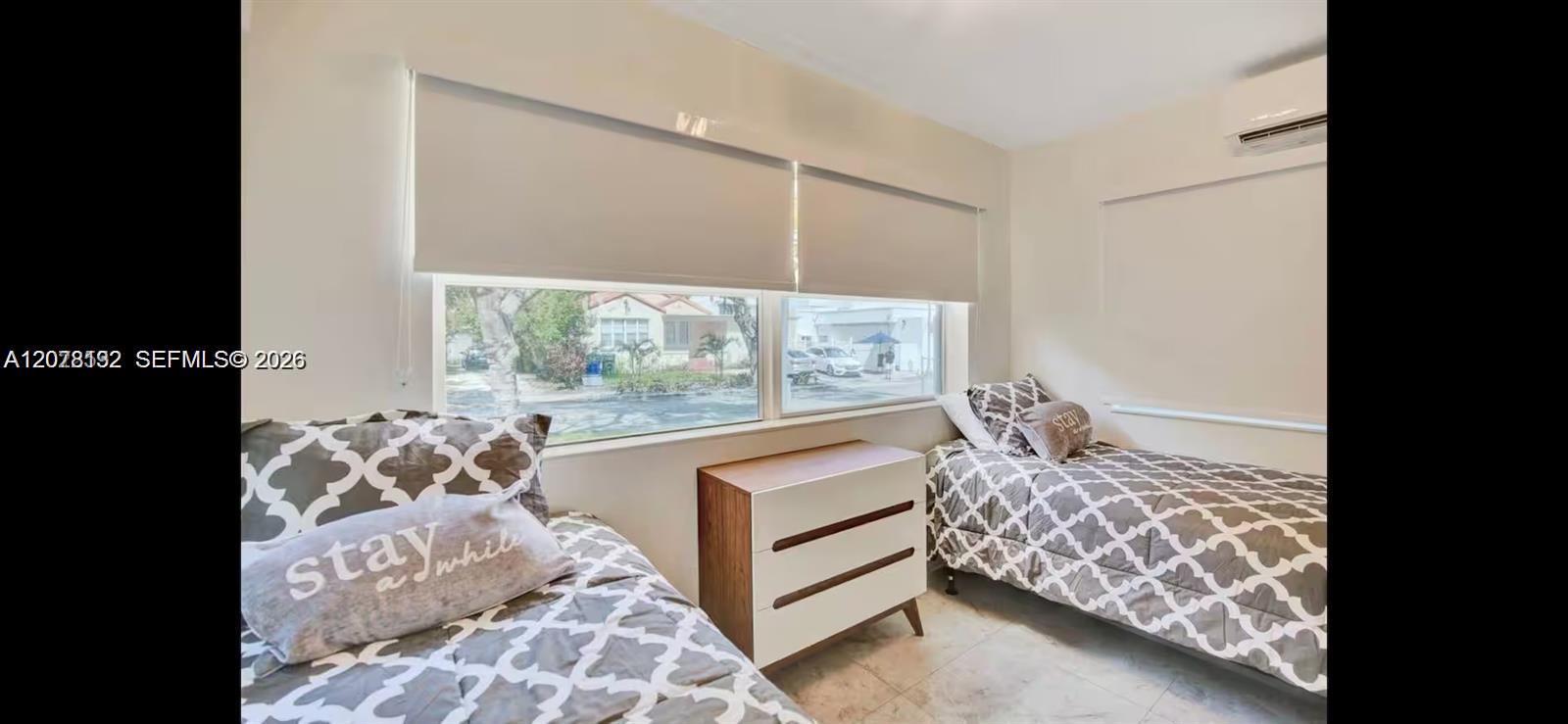 Bedroom with two single beds, patterned gray-and-white bedding, and a dresser between them.