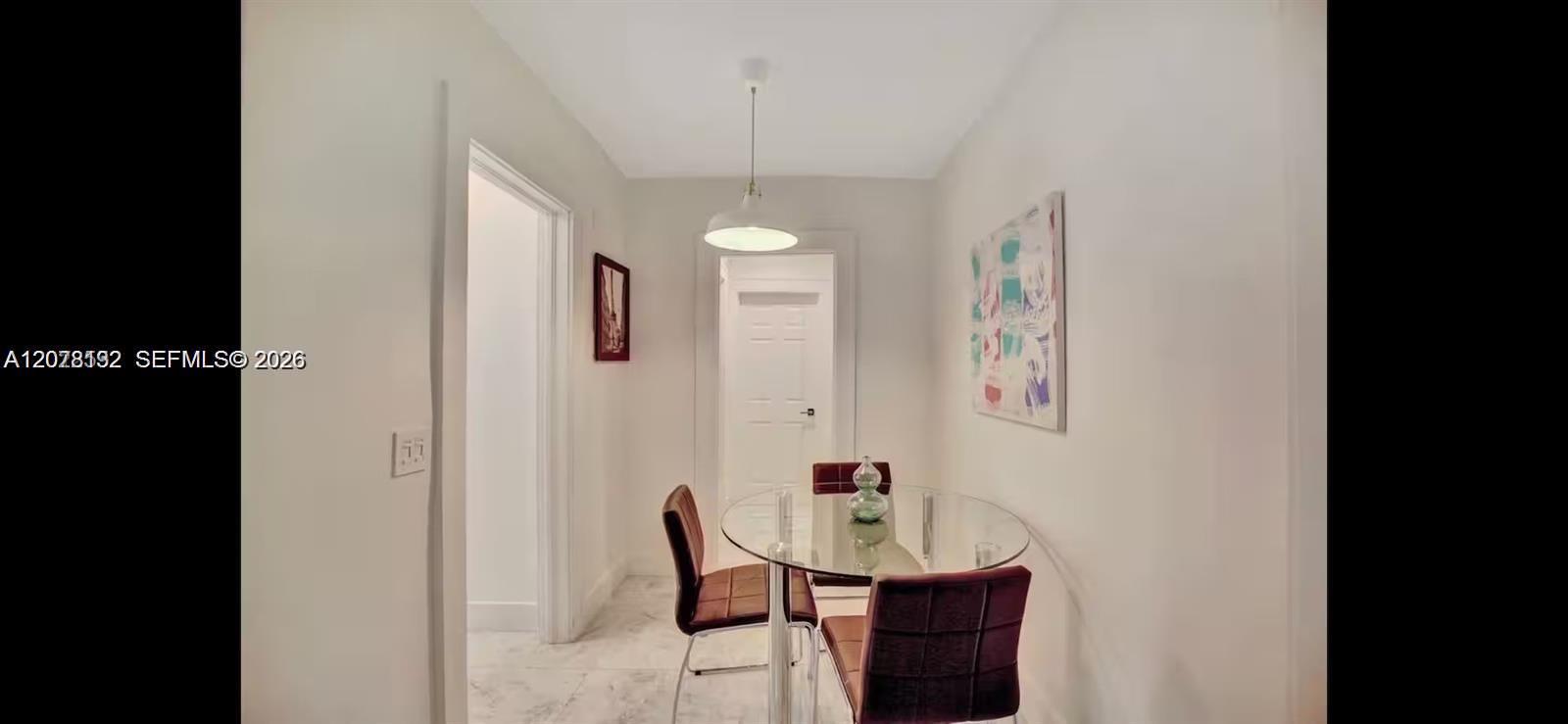 Dining area with a round glass table, dark chairs, and colorful wall art.