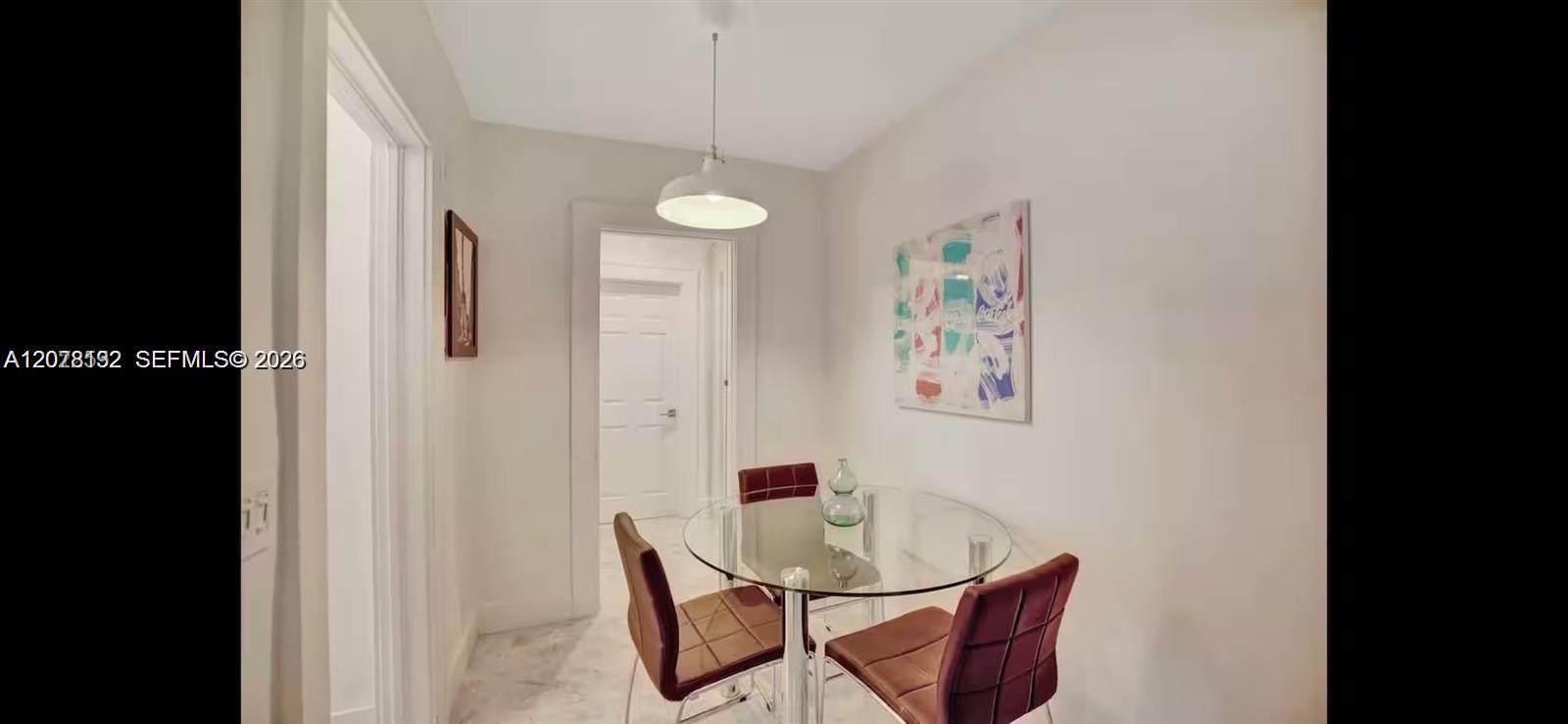 Dining area with a round glass table, burgundy chairs, and colorful abstract wall art.