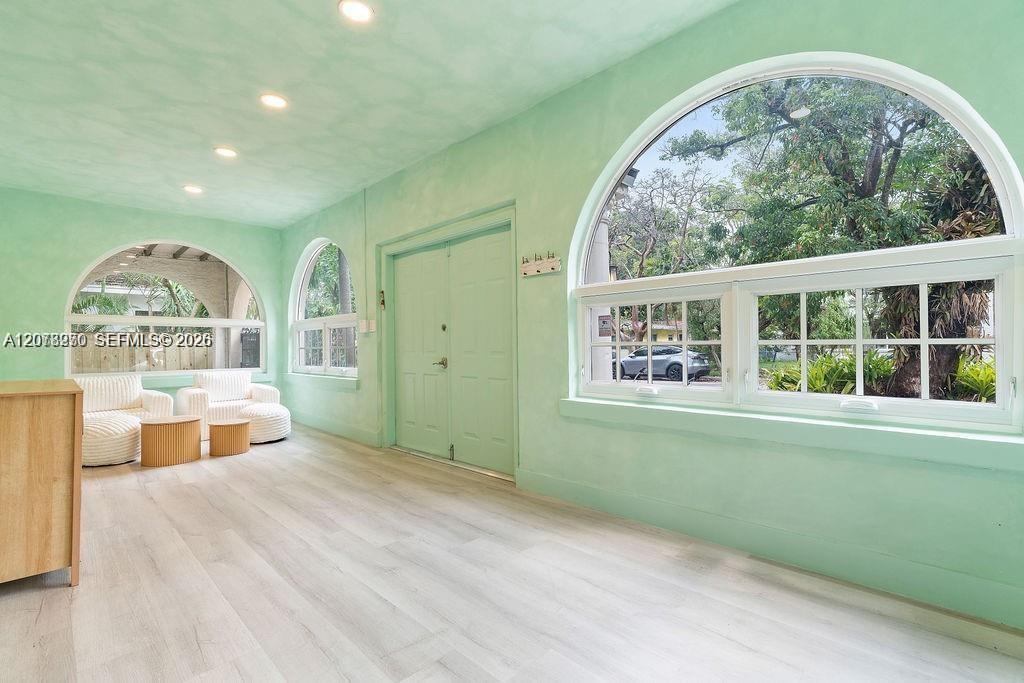 Mint-green room with arched windows, pale flooring, and a white curved sofa beneath an arched opening.