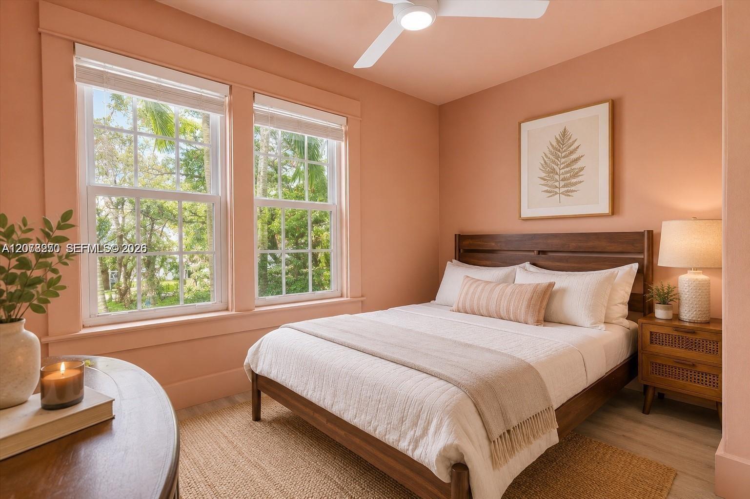 Bedroom with a dark wood bed, white linens, and two bright windows overlooking greenery.