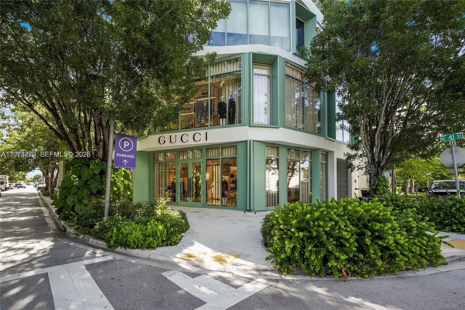 Modern Gucci storefront with a green-framed glass facade on a landscaped street corner.