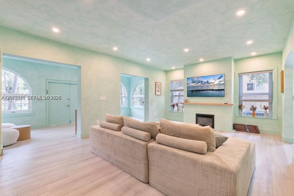 Living room with a beige sectional, fireplace, wall-mounted television, and arched openings.