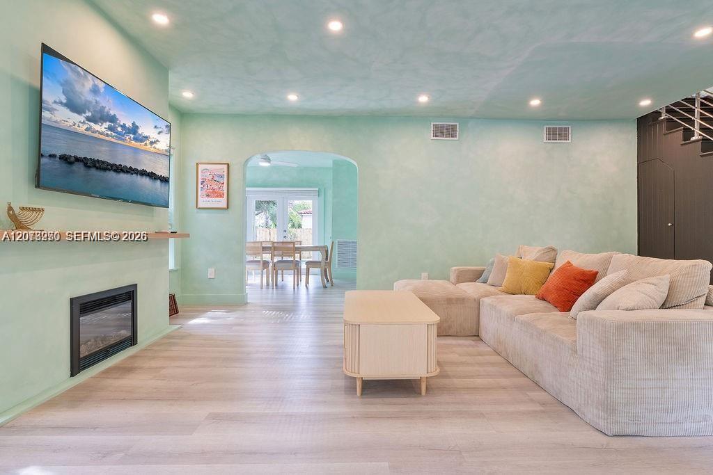 Living room with mint-green walls, a large sectional sofa, and an arched opening to the dining area.