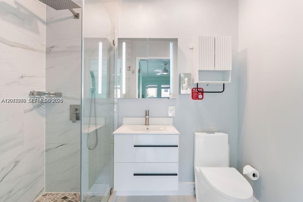 Modern bathroom with a glass shower, marble-look tile, and floating white vanity.
