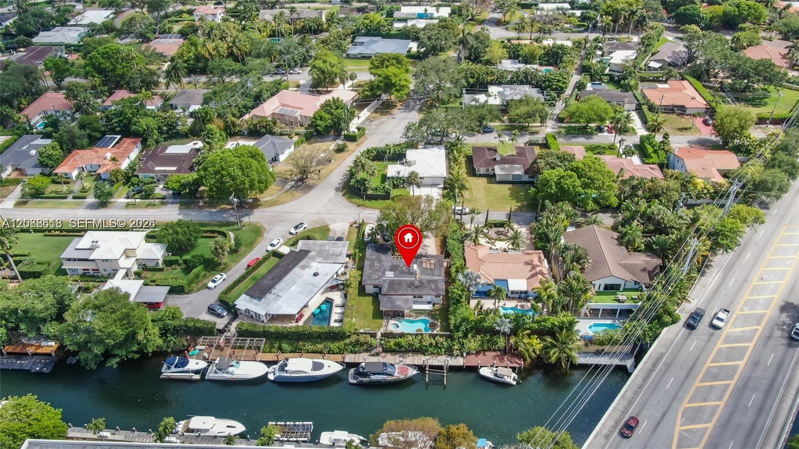 Aerial view of the marked home beside a canal, with docks, boats, and nearby pools.