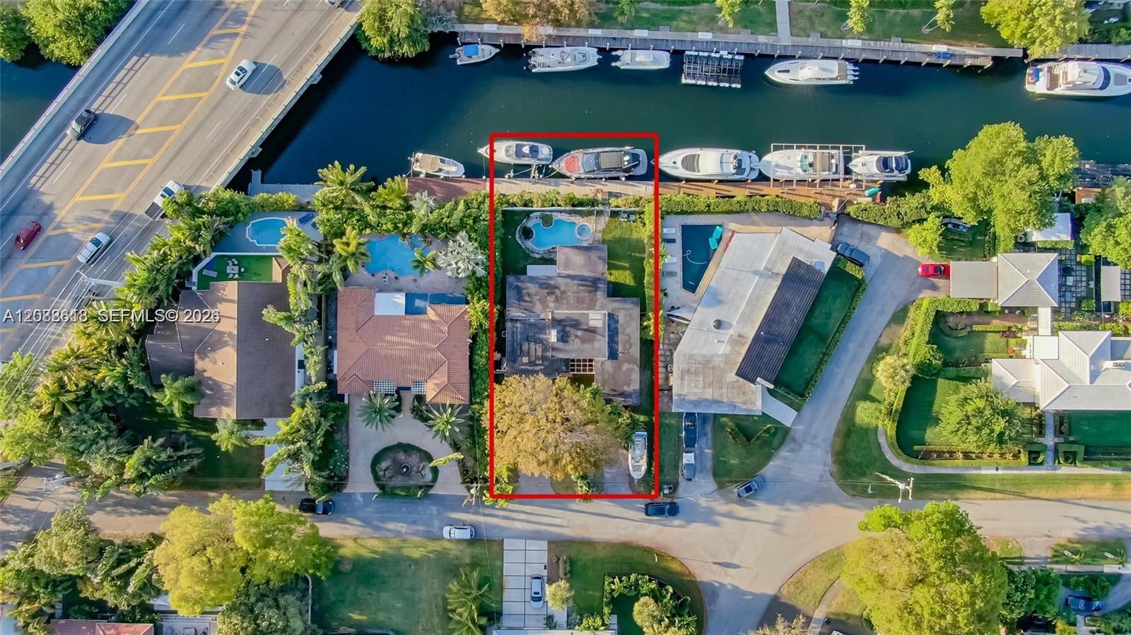 Aerial view of a canal-front home and pool, with the property outlined in red.
