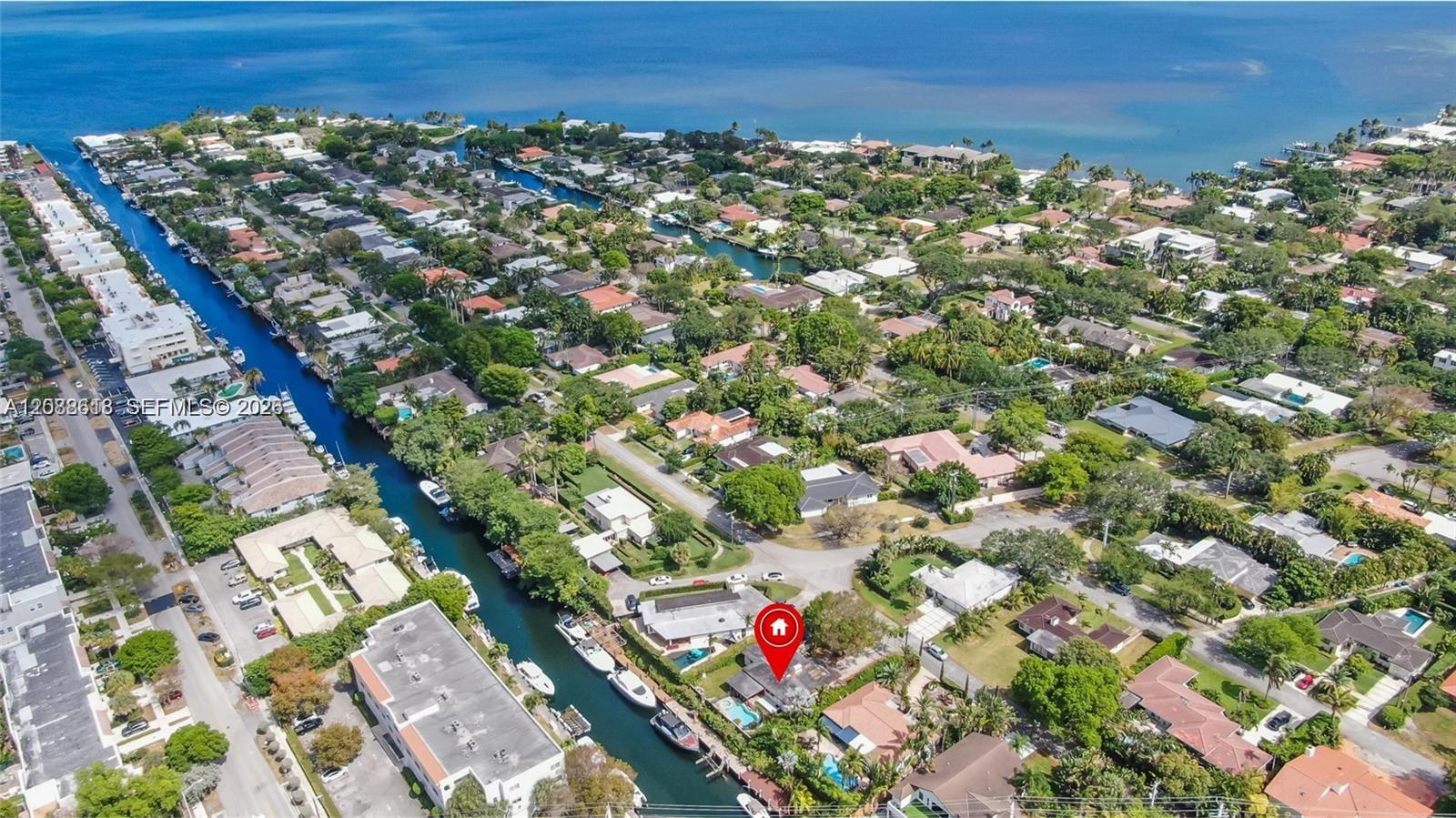 Aerial view of canal-front homes and boats, with a red map pin marking the property.