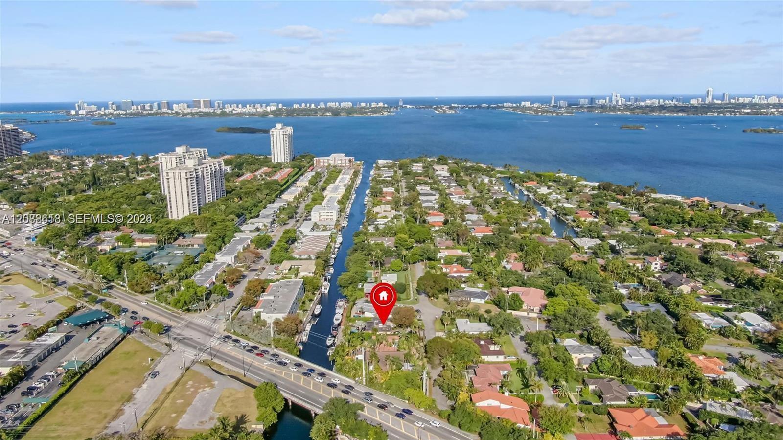 Aerial view of a canal-side Miami Shores neighborhood with Biscayne Bay and a distant skyline.